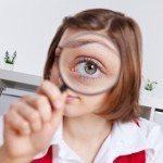 Picture of girl with magnifying glass over one eye to make it look much bigger